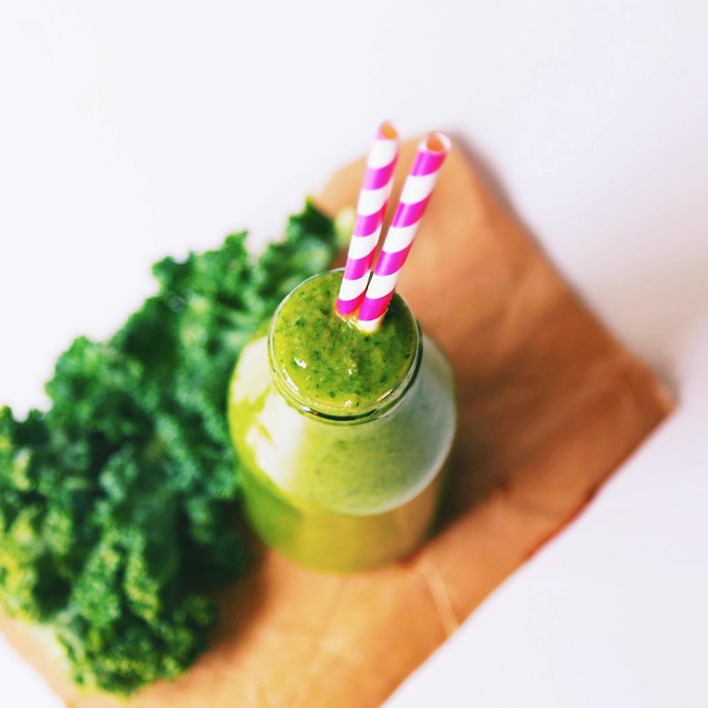 Top view of a delicious green smoothie with striped straws, perfect for a healthy diet.